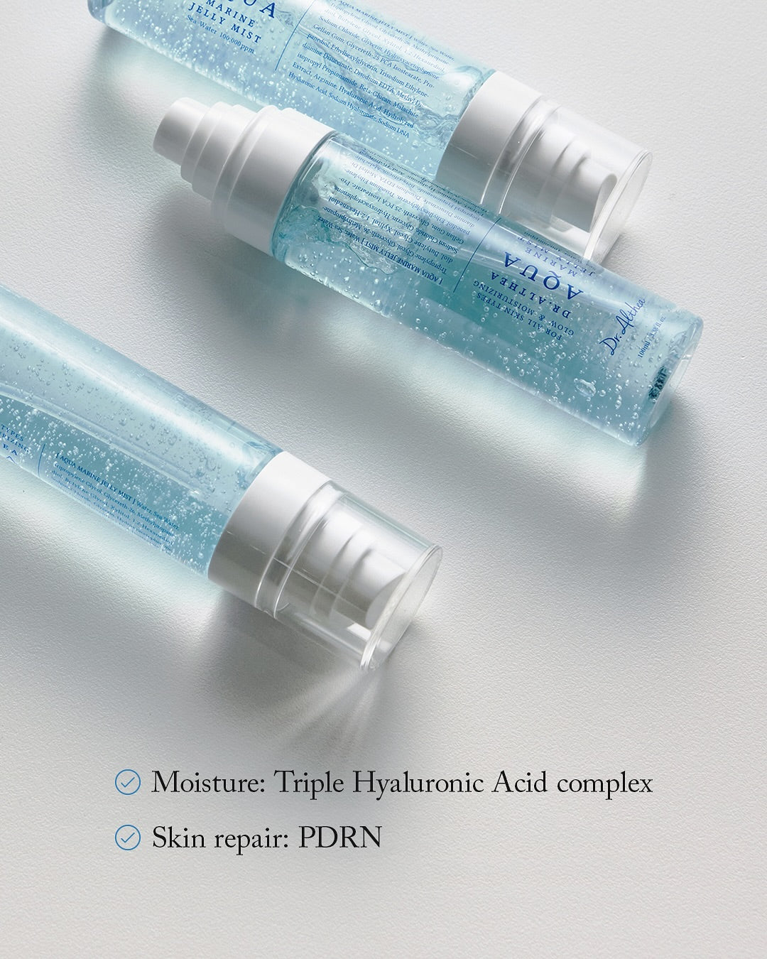 Mitinoša sejas želejmigla ar zilu krāsu, no YABUKO Dr. Althea Aqua Marine Jelly Mist, 100 ml, uz galda.